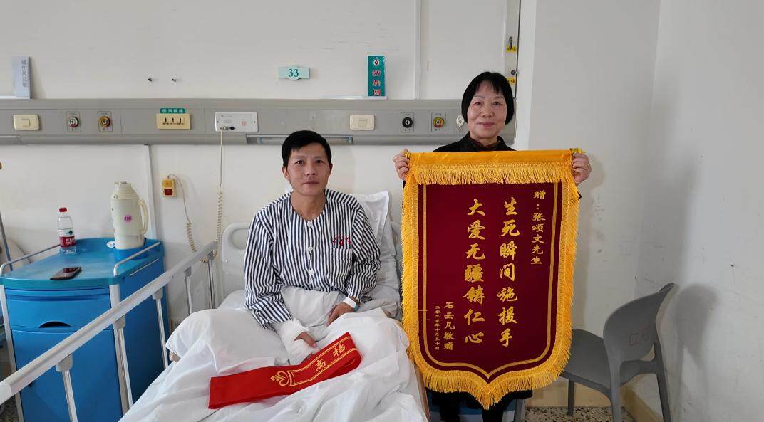 受伤者石云凡与母亲展示致谢锦旗