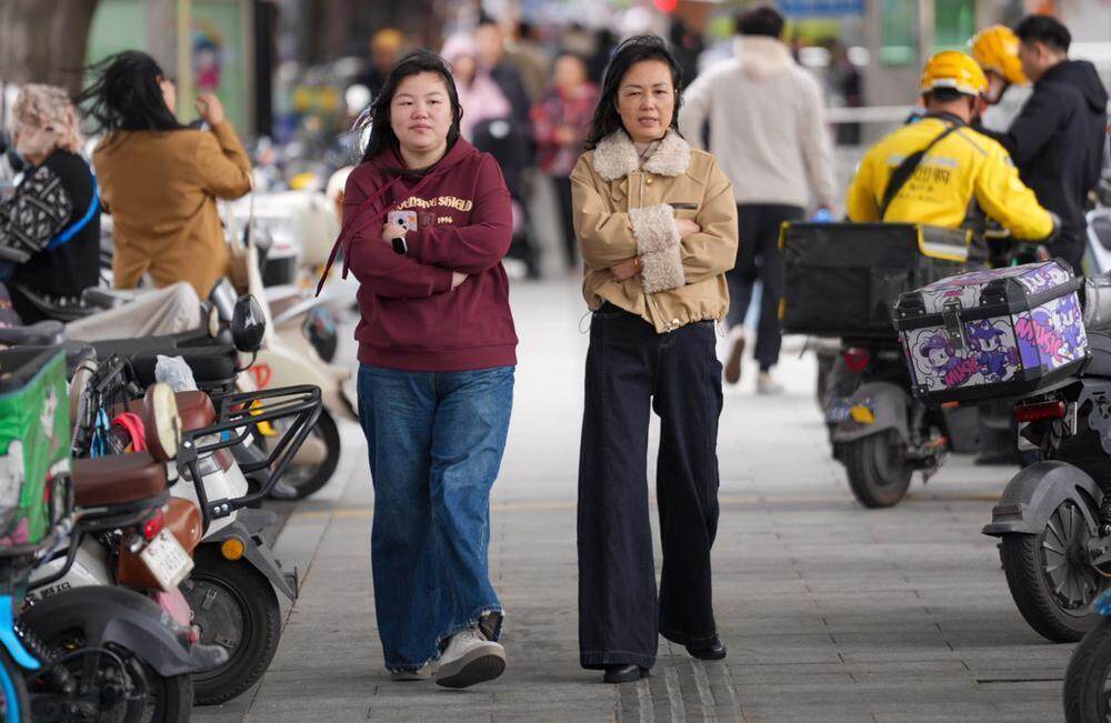 12月25日白天，广州市民穿厚衣搂身取暖出门 梁怿韬 摄