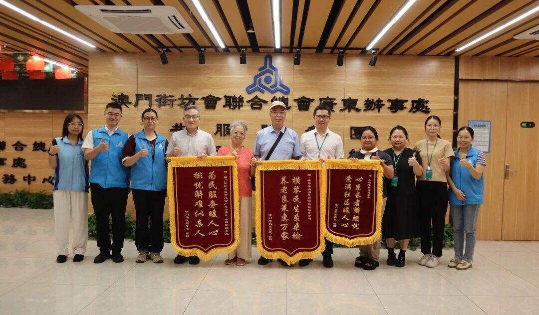  居住在小横琴社区的澳门居民梁爱花（将三面烫金锦旗分别交到了横琴粤澳深度合作区民生事务局（以下称“合作区民生事务局）”、小横琴社区居委会、澳门街坊会联合总会广东办事处小横琴服务点（以下称“澳街总广东办小横琴服务点”）工作人员的手中，以感谢各方分别给予的政策支持、关心帮扶与服务保障。