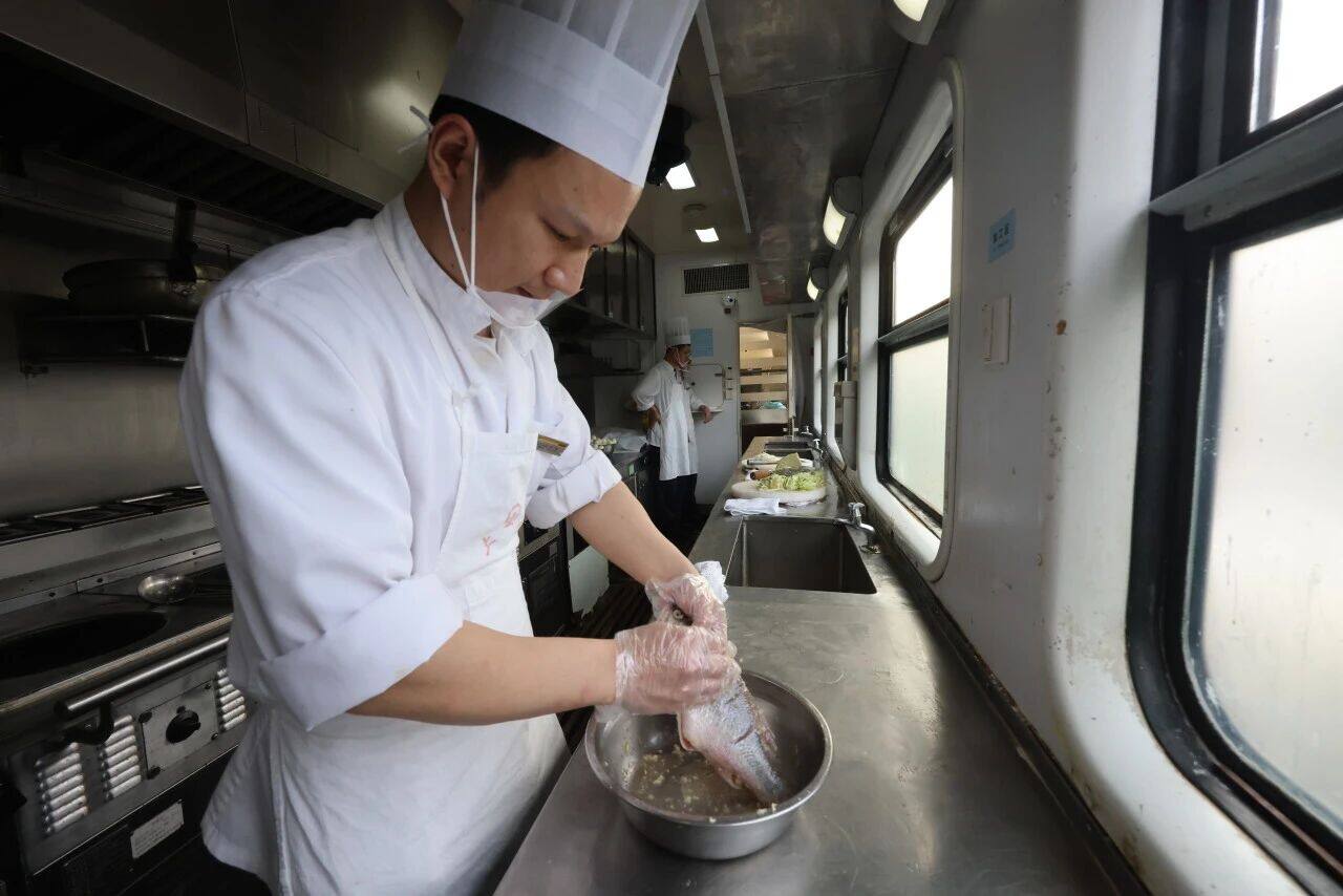  餐车的厨房里厨师正在准备制作红烧鲈鱼