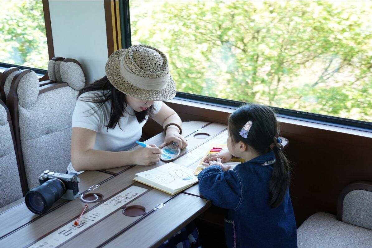 旅客在“大美上饶”主题观光列车上的童韵车厢里一同体验蚌壳绘画
