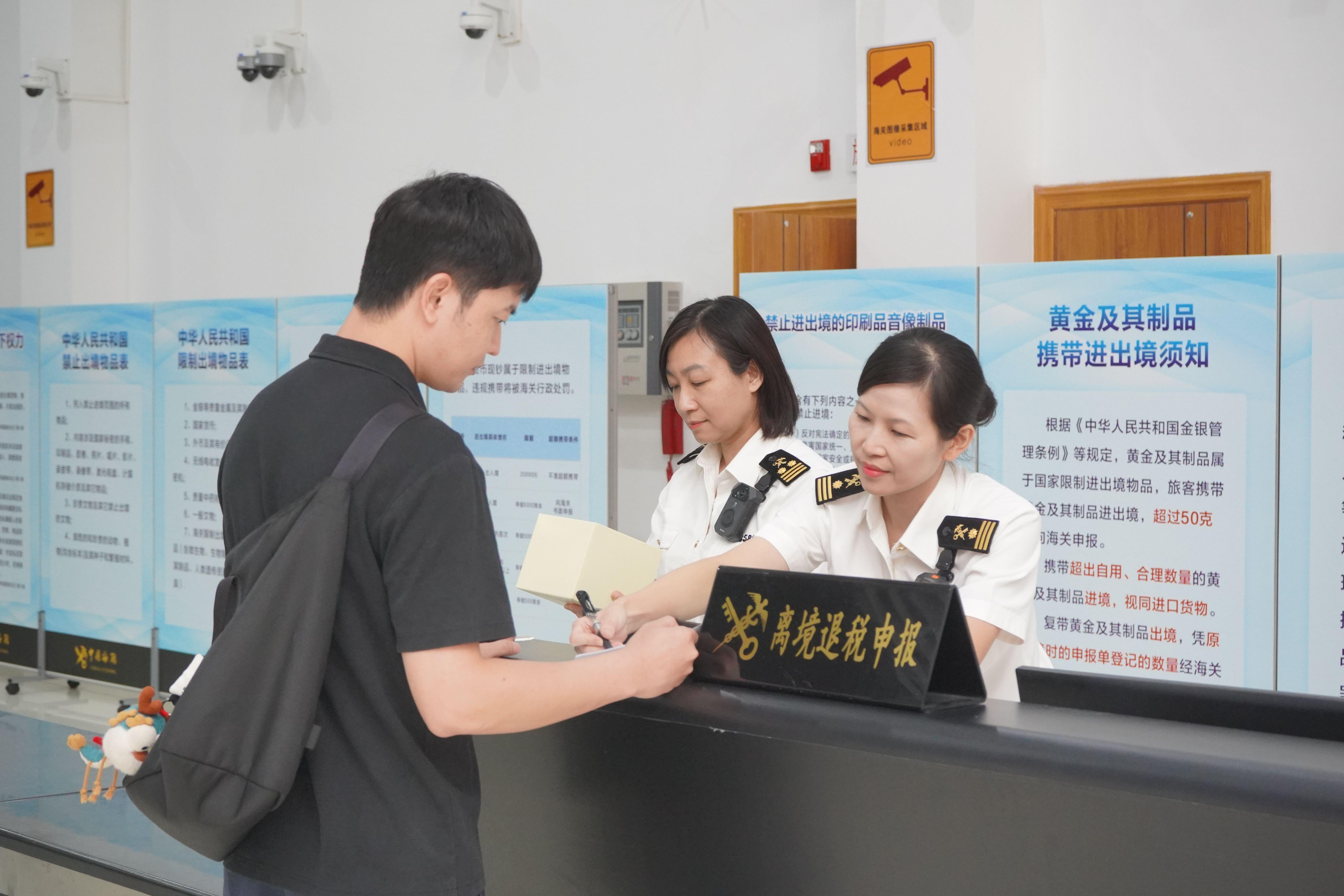 九洲海关关员在为旅客办理离境退税验核手续(丘权民 摄) 九洲海关关员在为旅客办理离境退税验核手续(丘权民 摄)
